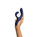 A hand holds the We-Vibe Nova 2 Powerful Flexible G-Spot Rabbit Vibrator, a dark blue silicone toy with dual prongs for clitoral and G-spot stimulation, against a plain white background.