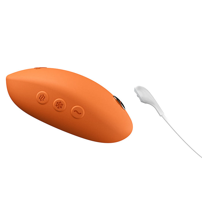 The We-Vibe Temp Lay On Vibrator with Hot and Cold Functions is an orange handheld device with three icon-marked buttons and a white wired attachment—perfect for temperature play as a heated or cooling vibrator.