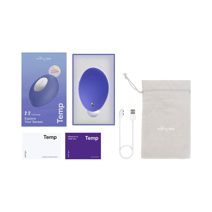 The We-Vibe Temp Lay On Vibrator with Hot and Cold Functions includes a purple oval-shaped vibrator, gray storage pouch, white USB charging cable, instruction cards, and packaging featuring “Explore Your Senses” and a product image.