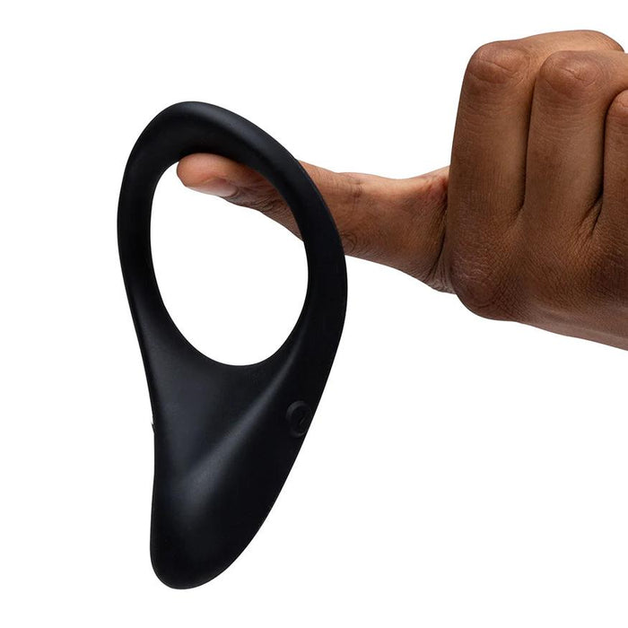 Black silicone We-Vibe Verge 2 cock ring held on a finger, showcasing its flexible, ergonomic teardrop design.