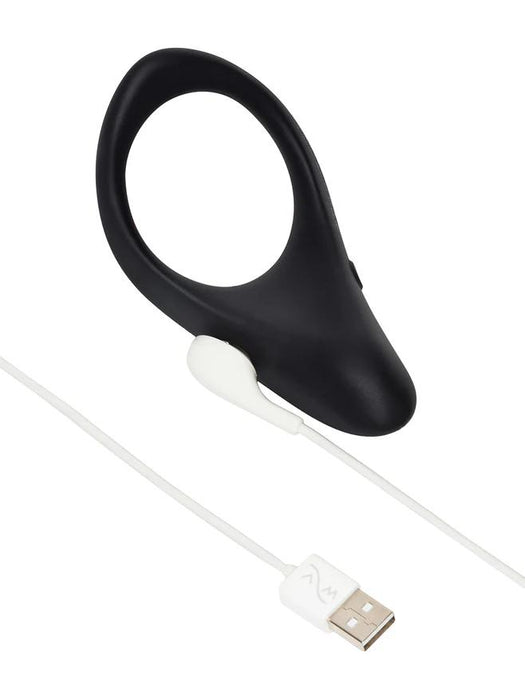 Black silicone We-Vibe Verge 2 vibrating cock ring with a magnetic white USB charging cable on a white background.