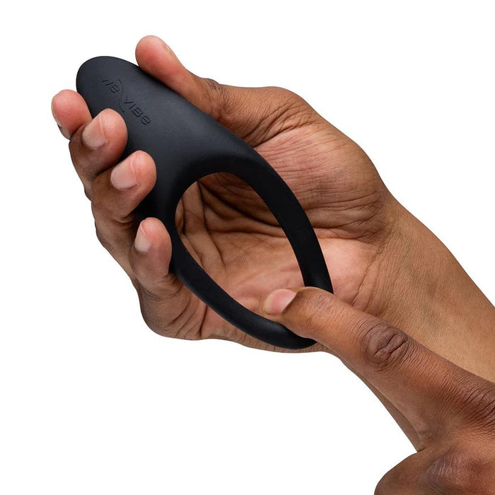Hand holding a flexible, black silicone We-Vibe Verge 2 vibrating cock ring with a smooth, ergonomic design.