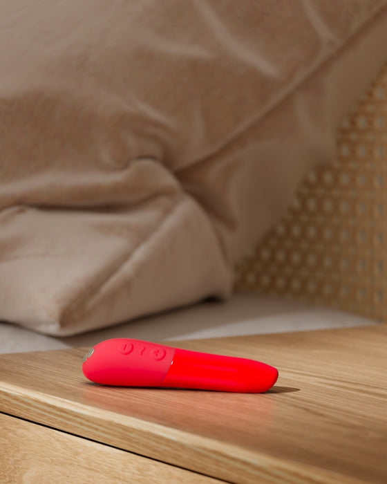 We-Vibe Tango X Powerful Bullet Vibrator - Red on wooden nightstand 