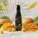 A bottle of Wicked Aqua Mango Flavored Water Based Lubricant is displayed with whole, sliced, and cubed mangoes, water splashes, and green leaves in the background, emphasizing this kissable water-based lubricant.