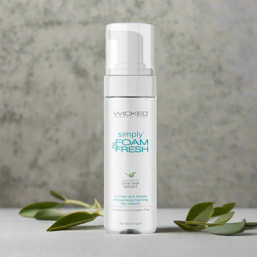 A 207 ml (6 fl oz) white bottle of Wicked Simply Foam And Fresh Toy Cleaner features a pump dispenser, contains olive leaf extract and essential oils, and is labeled alcohol and paraben-free.