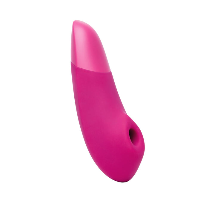 The Womanizer Enhance Pleasure Air + Vibration Clit Stimulator is a pink, curved handheld device with a small circular tip opening, seen on a white background. It uses Pleasure Air Technology for gentle stimulation.