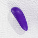 The Womanizer Starlet 3 Pleasure Air Clitoral Stimulator, a purple, water-resistant, oval-shaped device with buttons, is displayed on a rippled white surface and covered in water droplets.