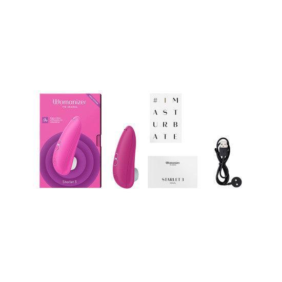 A pink Womanizer Starlet 3 Pleasure Air Clitoral Stimulator is displayed with its box, manuals, hashtag card, charging cable, and a small accessory, all neatly arranged on a white background.