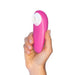 A hand holds the Womanizer Starlet 3 Pleasure Air Clitoral Stimulator, featuring a pink body and white circular tip, against a plain white background.