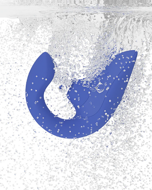 A blue object resembling a curved, ergonomic handle is partially submerged in water, creating a large splash of bubbles around it. The dynamic splashes capture the motion and energy of the moment, akin to how a Womanizer Womanizer Blend  Pleasure Air Clitoral & G-Spot Rabbit - Blue might enhance dual stimulation with G-spot vibrations.