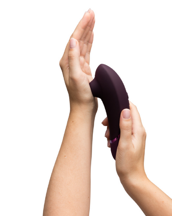 Model holding the purple womanizer next in their hand against other hand 