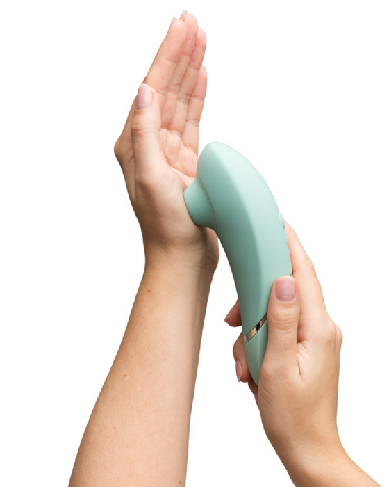 Womanizer Next  Pleasure Air Clitoral Vibrator - Sage Green in model's hand against other hand 