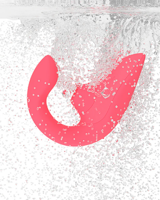 A bright pink, curved, abstract-shaped object, resembling the Womanizer Blend Pleasure Air Clitoral & G-Spot Rabbit - Rose by Womanizer, is submerged in clear water, surrounded by numerous small air bubbles. The water surface is partially visible at the top of the image. The object appears to be floating or possibly in the process of sinking or emerging.