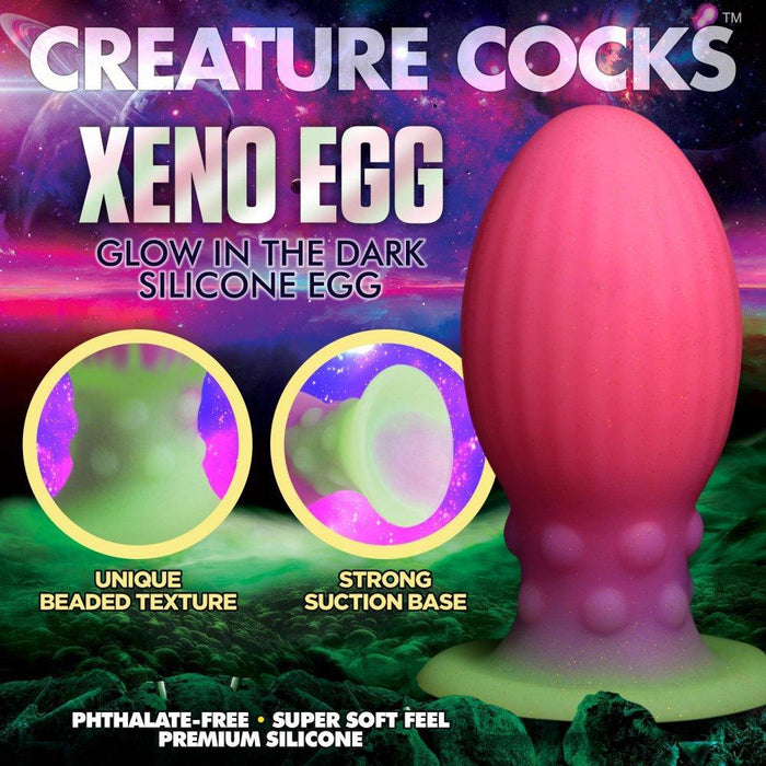A promo image for the "Xeno Egg Glow In The Dark Extra Large Thick Silicone Egg," featuring its pink and green beaded texture, strong suction base, and glowing effect on a vibrant space-themed background with features highlighted.