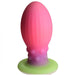 The Xeno Egg Glow In The Dark Extra Large Thick Silicone Egg features a ribbed pink body, a textured base with round bumps, and a flat green suction cup bottom.