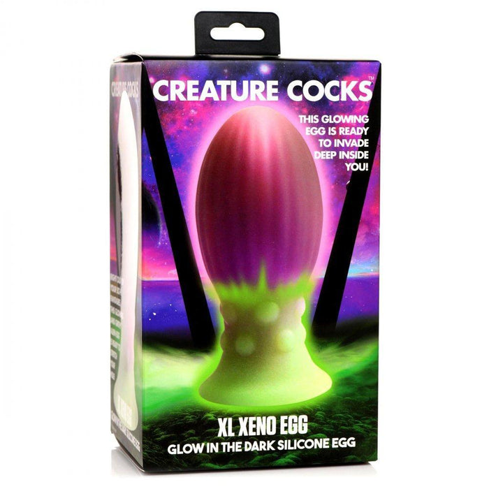 The image displays packaging for the "Xeno Egg Glow In The Dark Extra Large Thick Silicone Egg," featuring a fantasy design in purple, green, and pink with detailed product information.