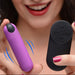 A smiling woman holds a BANG! Vibrating Bullet with Remote Control: the small, powerful purple bullet in one hand, the black buttoned remote in the other. Her red nails and lips pop, with blue motion lines highlighting its vibrant sensations.