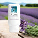 A bottle of Aloe Cadabra French Lavender Aloe Based Gentle Lubricant 2.5 oz rests on a wooden surface by fresh lavender, with a blurred lavender field and mountains behind, highlighting its organic aloe vera formula for pure relaxation and comfort.