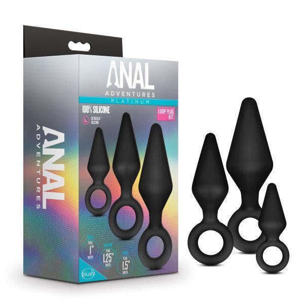 The Blush "Anal Adventures Silicone Loop Anal Training Butt Plug Set" is displayed as a boxed set of three black silicone anal plugs with finger-loop handles. The packaging showcases the body-safe, black tapered plugs in various sizes on the front of the box and emphasizes that they are made of 100% silicone.