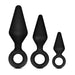 The Anal Adventures Silicone Loop Anal Training Butt Plug Set from Blush is displayed, featuring three black tapered plugs arranged from large on the left to small on the right. Made of body-safe silicone, each plug has a tapered tip and a flared base with a circular handle for easy removal.
