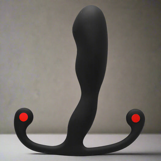 A black, ergonomically designed object with a curved, bulbous body features two loop handles at the base—one marked with a red dot and the other with a white dot, indicating different functions of the Aneros Helix Syn Trident Hands-Free Prostate Stimulator from Aneros.