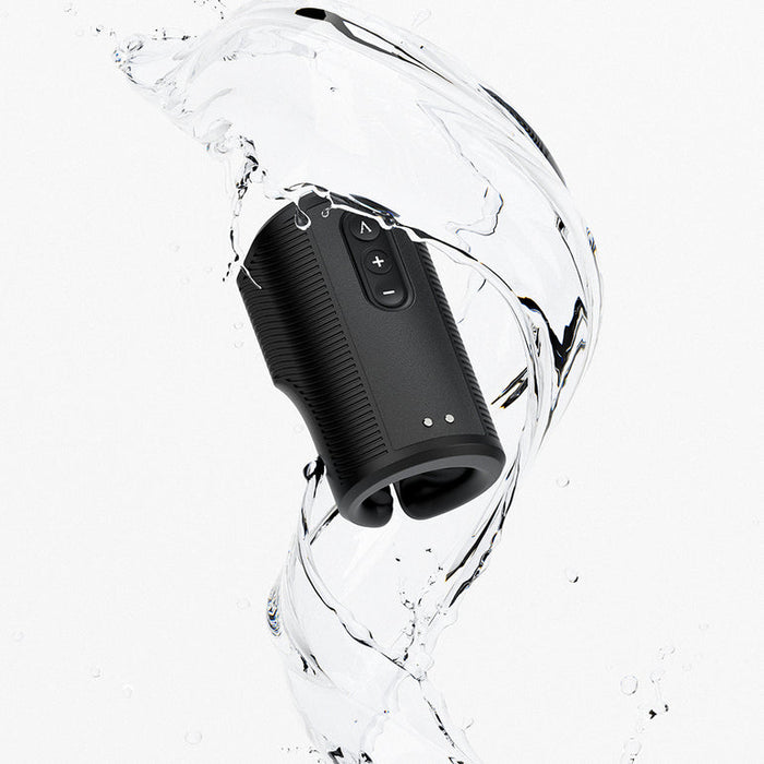 A black portable speaker with visible control buttons is splashed by water, emphasizing its water resistance—perfect for music on the go, much like the convenience and innovation of the Arcwave Zing Adjustable Vibrating Silicone Masturbator.