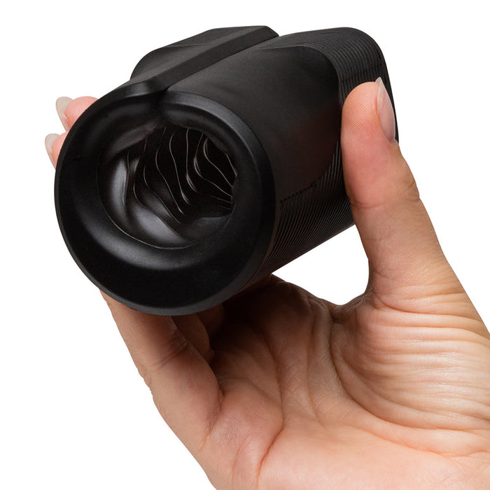 A hand holds the Arcwave Zing Adjustable Vibrating Silicone Masturbator, a black cylindrical stroker with a textured grip and spiral-patterned opening, against a plain white background.
