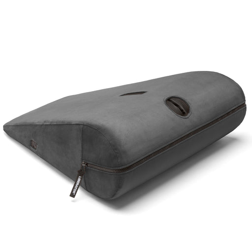 The Liberator Axis Magic Wand Hands-Free Sex Toy Mount is a gray, wedge-shaped pillow with a zippered cover, built-in handle, and a small circular plastic window on top for hands-free Magic Wand use.