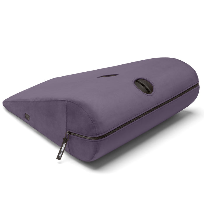 The Liberator Axis Magic Wand Hands-Free Sex Toy Mount is a purple, wedge-shaped ergonomic pillow with a side zipper, small handle, and oval cutout—ideal for comfortable, hands-free use of your wand and added versatility.