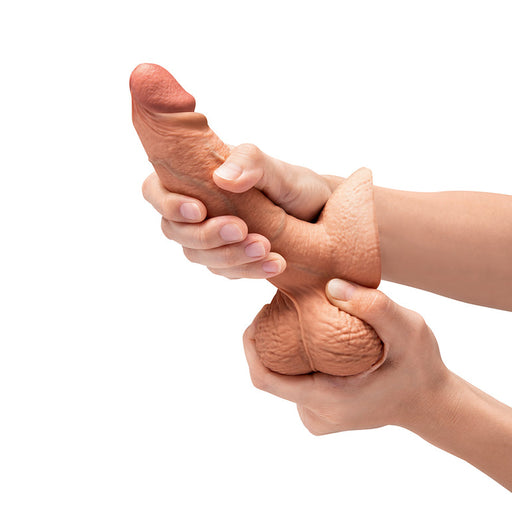 Someone holding the b-Vibe Slipskin Realistic 6 Inch Girthy Silicone Dildo in Caramel, which features a lifelike design that looks just like the real thing.