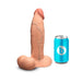 The b-Vibe Slipskin Ultra Realistic Girthy 9 Inch Medium Tone Silicone Dildo stands upright beside a blue soda can for size comparison, displayed against a plain white background.