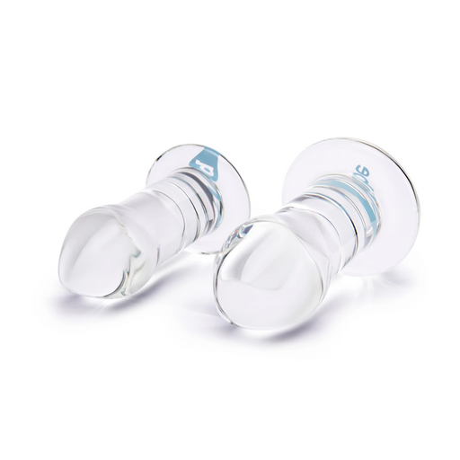 Two clear borosilicate glass anal dilators of different sizes with smooth, tapered designs and wide bases.
