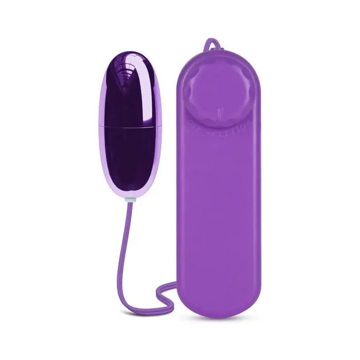 The B Yours First Time Wired Remote Control Power Bullet Vibrator by Blush is a purple, cylindrical vibrating egg connected to a matching handheld remote with a single dial. This multispeed bullet features an off position and settings for increasing intensity, making it ideal for clitoral stimulation. Both the egg and the remote are linked by a thin, flexible wire.