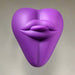 The Bananapants Kissi Dildo Base features sculpted lips and a tongue on a heart-shaped, purple body made from body-safe silicone, shown against a white background with a sleek, modern design.