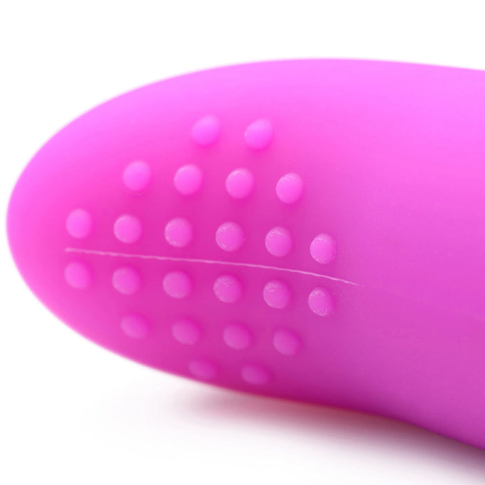 Close-up of the tip of a purple, remote-controlled bullet vibrator from the BANG! Couple's Cock Ring, Finger Vibe, Bullet & Blindfold Kit by XR Brands. The tip features small, raised dots in a pattern at the end, with a smooth surface except for the textured area with the dots. The object appears to be part of a personal care item or intimate device set.
