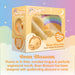 A product box for "Bean Blossom Unicorn Shaped Licking Tongue Vibrator - Yellow" by Creative Conceptions, a mini unicorn-themed vibe made of waterproof silicone. The front of the box features an image of the product, a QR code, and text describing it as magical and dreamlike. The background includes a rainbow, stars, and clouds.