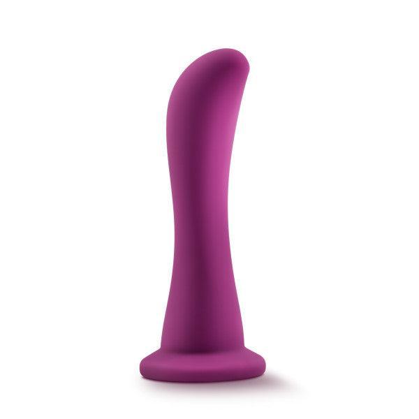 Introducing the Bellatrix 6.25 Inch G-Spot and Prostate Dildo by Blush in a striking Plum Purple hue, designed with a curved, tapered silhouette and a sturdy flared base for optimal g-spot excitement. The elegant toy stands upright against a simple white backdrop.