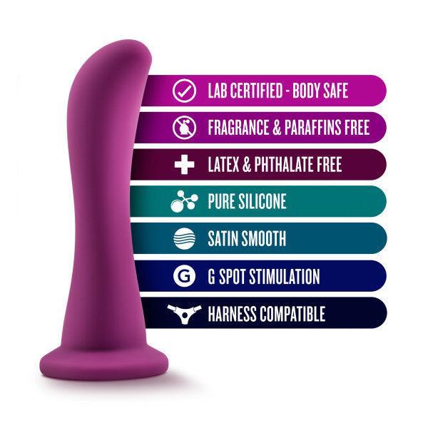 The Bellatrix 6.25 Inch G-Spot and Prostate Dildo in Plum Purple by Blush is showcased alongside a list of features emphasizing its qualities: lab certified and body safe, free of fragrances and paraffins, latex and phthalate free, made from pure silicone with a satin smooth finish. It offers G-spot stimulation, is harness compatible, and is ideal for both G-spot and prostate stimulation.