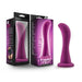 A plum purple, curved silicone dildo with a flared base is displayed beside its packaging. The packaging features a similar image of the dildo, along with the brand name "Blush" and detailed product information, highlighting its design for g-spot stimulation or prostate stimulation. The product name "Bellatrix 6.25 Inch G-Spot and Prostate Dildo" is also prominently shown.
