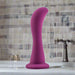 The Bellatrix 6.25 Inch G-Spot and Prostate Dildo from Blush stands upright against a white background in its elegant plum purple hue. Its smooth, curved silicone structure with a flared base promises both G-spot stimulation and unforgettable pleasure through its ergonomic design.