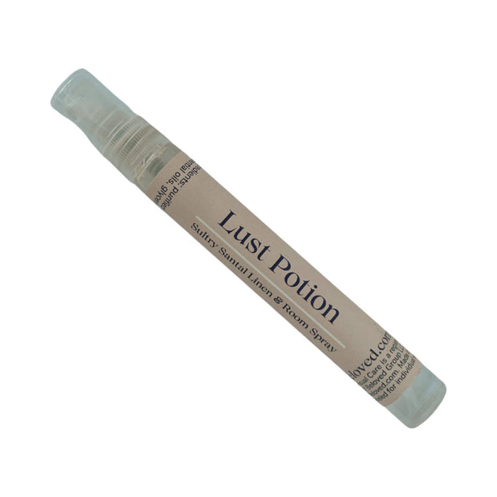 A small, clear "Lust Potion" spray bottle labeled "Sultry, Sandal Linen & Room Spray," part of the Beloved Vacation Lovin' Intimacy Kit—an ideal sensual essential for travel, shown against a white background.