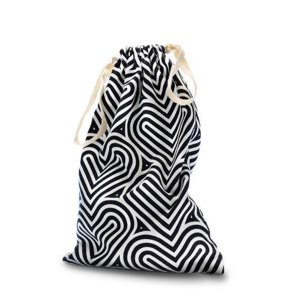 The Blush Bomba Black & White Hearts Sex Toy Storage Bag, featuring a black and white geometric heart pattern, is perfect for discreet sex toy storage. This drawstring bag from Blush is cinched at the top with cream-colored drawstrings, stands upright against a plain white background, and is machine washable for easy care.