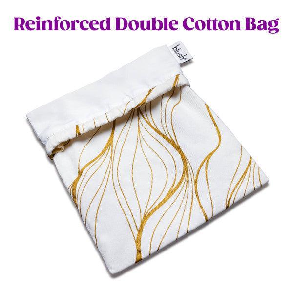 The Blush Embrace White & Gold Toy Storage Bag, made from double-layer white cotton, features a fold-over top adorned with a golden swirl pattern and a drawstring tie closure. A small white tag is displayed with the brand name "Blush" on it. The header above the bag reads "Reinforced Double Cotton Bag" in purple text. This versatile bag is ideal for use as either a cotton toy bag or for sex toy storage.
