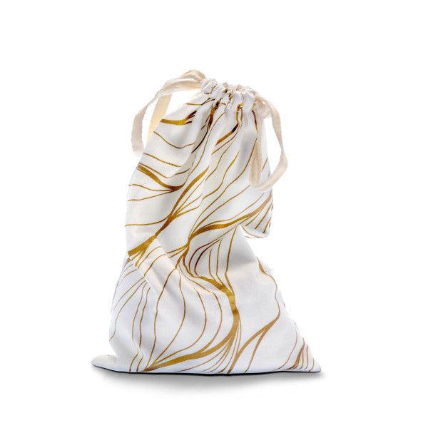 Introducing the Blush Embrace White & Gold Toy Storage Bag by Blush. This small, stylish drawstring bag features a delicate gold leaf pattern on a crisp white background. When the drawstring tie is pulled, it creates soft folds in the fabric, with shimmering gold lines forming gentle curves and swirls. Perfect for storing sex toys, this elegant bag stands upright against a plain white backdrop.