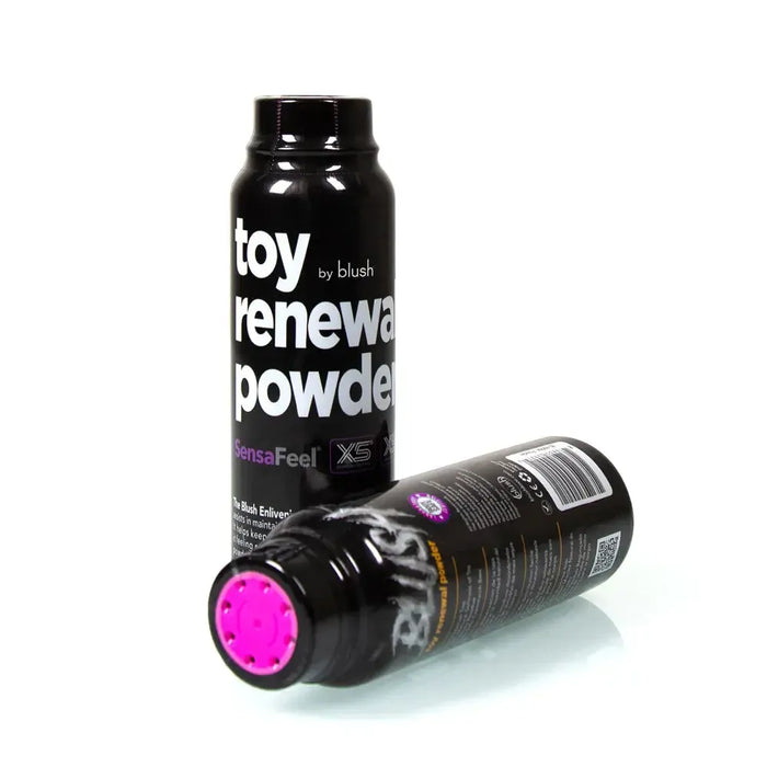 Two bottles of "Blush SensaFeel & TPE Toy Renewal Powder 3.4 oz" are displayed. One bottle is positioned upright, and the other is lying horizontally with its cap facing outward. The labels highlight the "SensaFeel" and "TPE" features. Perfect for maintaining self-lubricated toys, these dusting powder bottles feature a sleek black design with white and pink text.