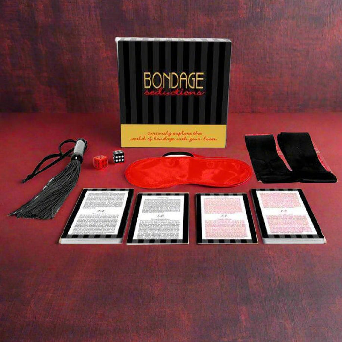 Bondage Seductions Board Game: A beginner couples kit with a whip, red blindfold, black restraints, dice, instruction cards, and game box—ideal for adventurous play on a red surface.