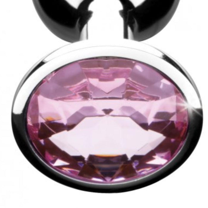 A close-up of a metallic pink gemstone set in a circular silver setting echoes the exquisite finish of Booty Sparks Pink Gem Aluminum Butt Plug. The gem's faceted surface reflects light from various angles, hinting at adventurous pleasures.