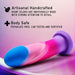 A colorful, flexible silicone dildo with shades of pink, blue, and purple is displayed on a gradient background. Text reads "Blush: Borealis Dreams 7.75 Inch Girthy Silicone Dildo - Cotton Candy," and "Artisanal Handcrafted: Avant dildos are individually made with strong attention to detail," along with "Body Safe: Phthalate free, lab tested and certified." Additionally, these dildos feature a powerful suction cup for versatile use.
