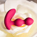 The Bubble Butt Inflatable Vibrating Butt Plug with Remote by Evolved Novelties, crafted from pink, body-safe silicone and featuring a curved base with two rounded bulbs, rests delicately on a soft, white rose. The petals of the rose form a gentle cradle around the plug, creating a captivating blend of elegance and modern design in the image.