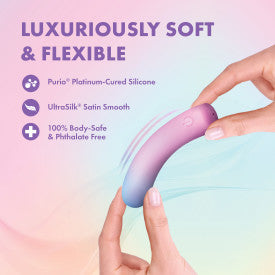 A hand bends the Play With Me Berry Burst Soft Flexible Bullet Vibrator—a curved, gradient-hued silicone toy—against a pastel background. Text reads: “Luxuriously soft & flexible,” made of waterproof, body-safe silicone with a smooth satin finish.
